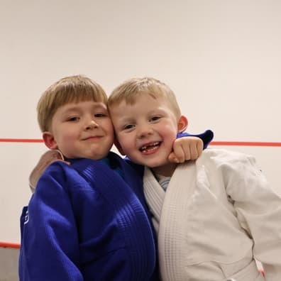 Two young students smiling together after a Jiu-Jitsu class at McGuigan's School of BJJ in Longridge